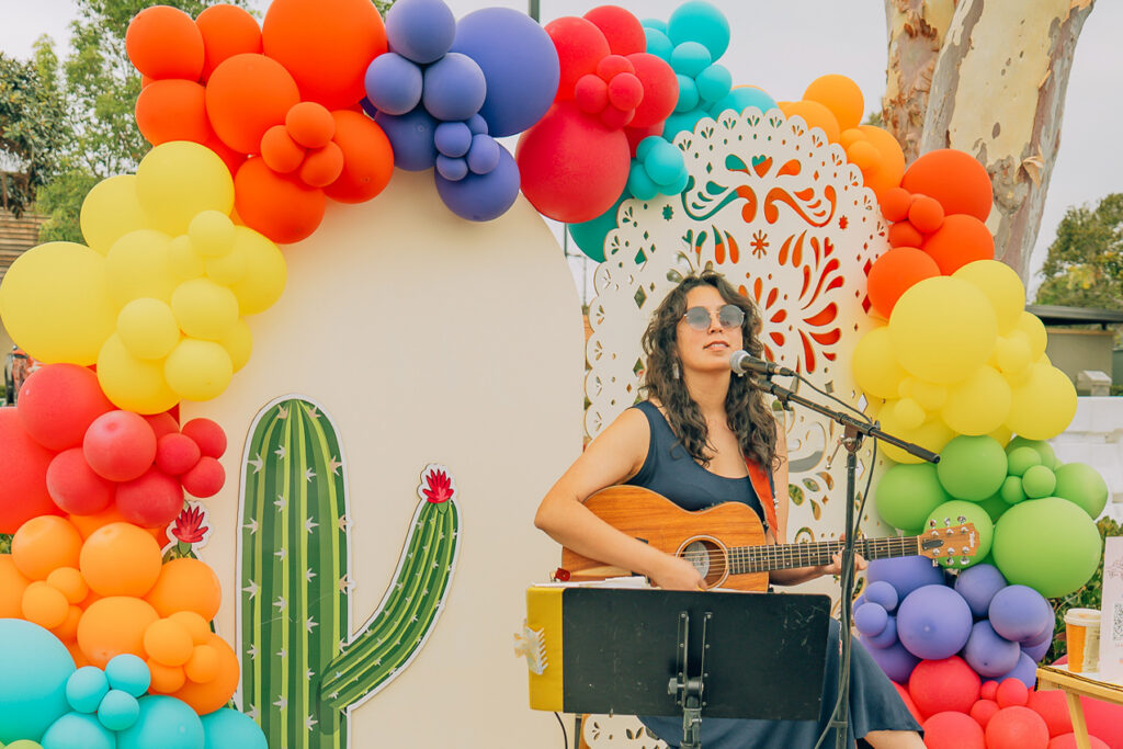 Woman singing and playing guitar at Dreamers Market
